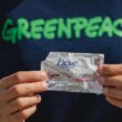 man with a greenpeache shirt holding a dove plastic sachet packaging