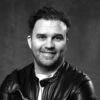 Black-and-white portrait of smiling man in leather jacket